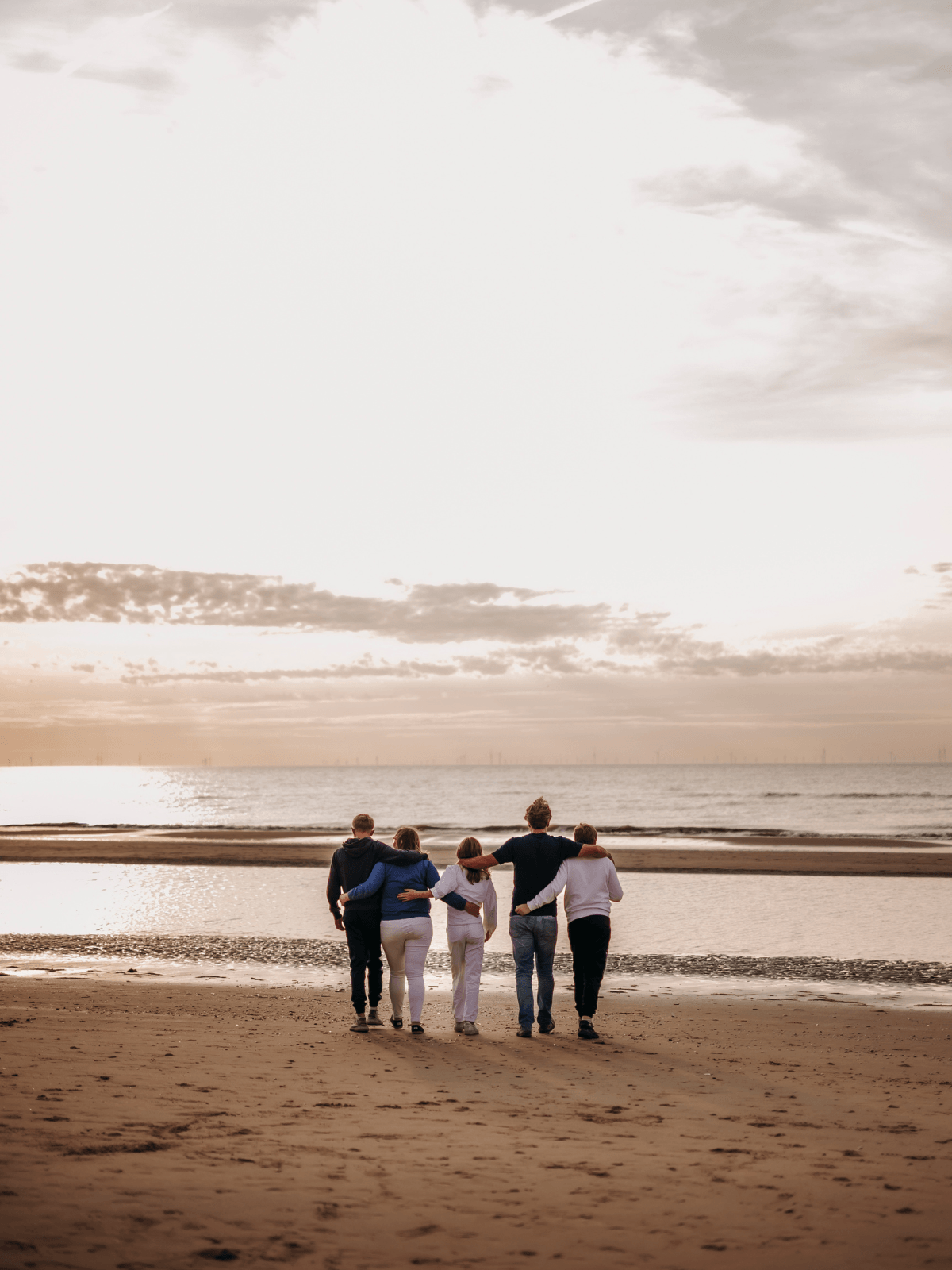Gezin wandelt in verbinding op het strand, een voorbeeld van rust in huis door Human Design.