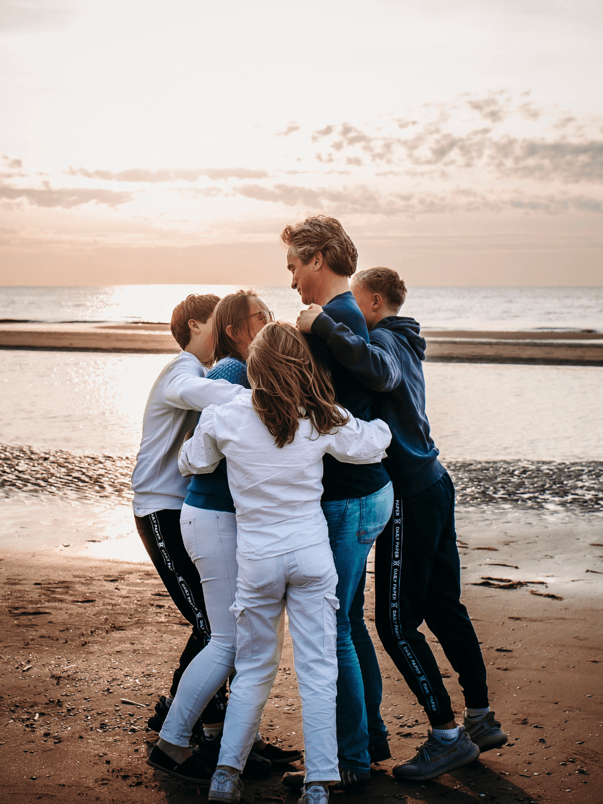 Human Design coach Rinskje knuffelt met haar gezin op het strand, als visualisatie van hoe ze rust en begrip vond in haar moederschap.