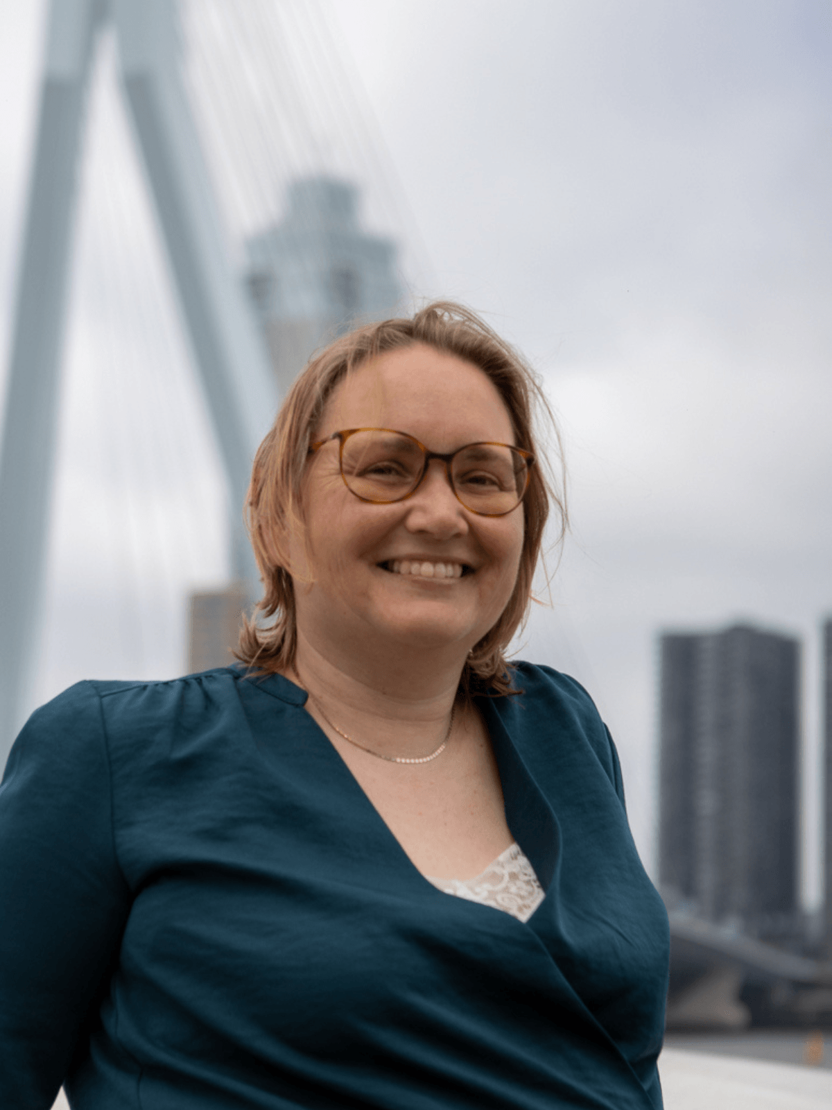 Human Design coach Rinskje lacht voor de Erasmusbrug; een knipoog naar haar achtergrond als Fries in de Randstad.